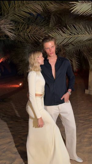 Lena Perminova hugs Taras Romanov, both looking at each other with affection, creating a moment of emotional intimacy between them.